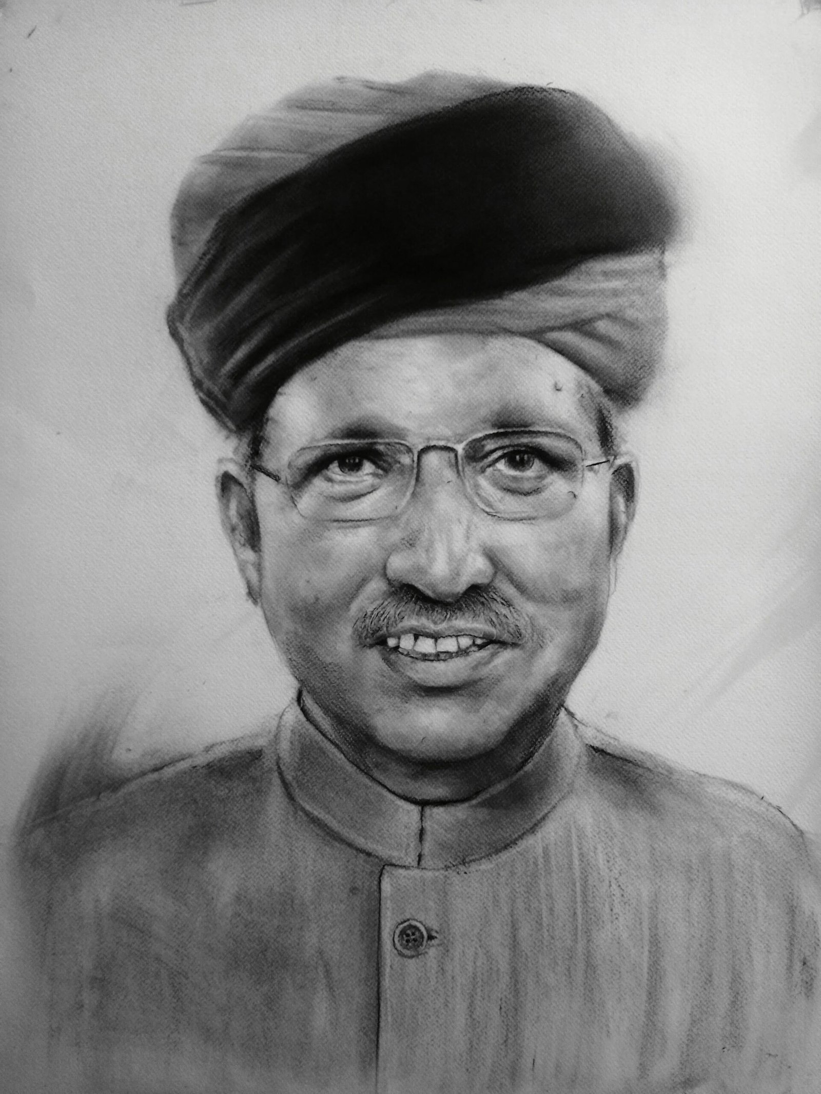 Durgesh standing between two large charcoal turban portraits at an exhibition